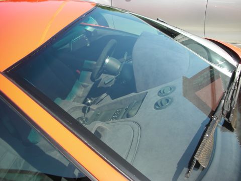 1998 Ford Crown Victoria - The interior of an orange sports car is visible through the windshield, showing the steering wheel and center console.