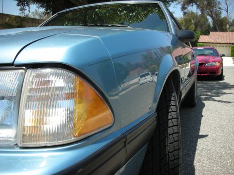 1998 Ford Crown Victoria - A blue coupe is parked on a residential street, with a red car visible in the background.