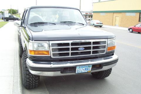 1996 Ford Bronco - Front view of a black Ford F-Series truck with a chrome grille and aftermarket tires.