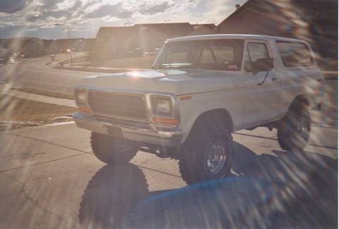 1979 Ford Bronco - This lifted Ford Bronco is parked in a suburban driveway under a cloudy sky.
