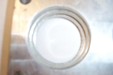 1996 Ford Bronco - Extreme out-of-focus close-up of one large round bore machined through an aluminum plate, with a counterbored bolt hole visible at the uppe…