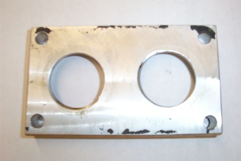 1996 Ford Bronco - A machined aluminum carburetor spacer or adapter plate photographed flat against a light background, showing two large round bores, four co…