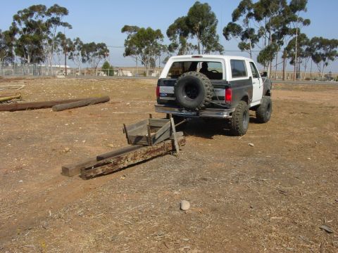 1994 Ford Bronco - Three-quarter rear view of a lifted two-tone white-over-gray full-size Ford Bronco with a hardtop, tailgate-mounted spare on a black wheel,…