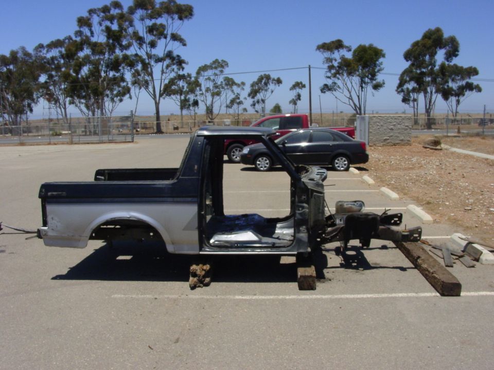 Pickup truck body, missing engine and interior, parked outside
