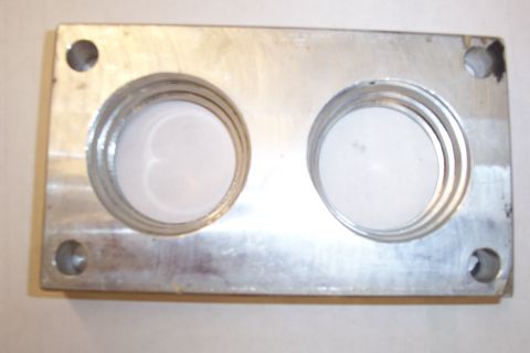1996 Ford Bronco - The opposite face of a machined aluminum two-bore adapter or carburetor spacer plate, showing stepped and threaded-looking counterbores aro…