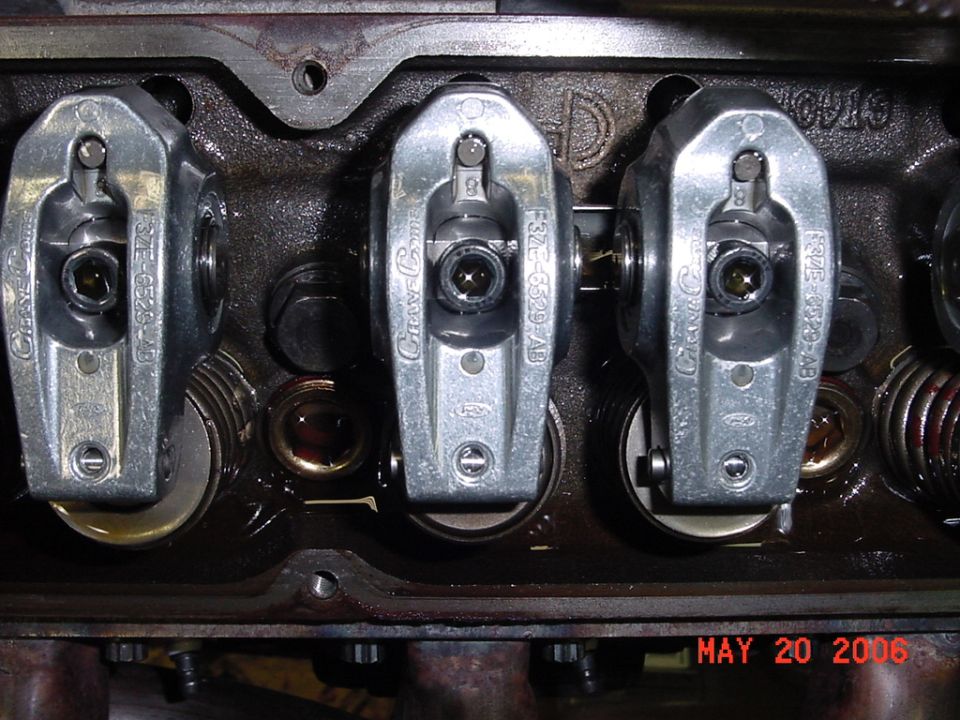 Close-up of engine valve train with three rocker arms visible. Part numbers F3TE-6529-AB are stamped on the rocker arms