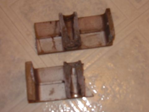 2000 Chevrolet Tahoe - Two rusty metal brackets are shown on a tiled surface.