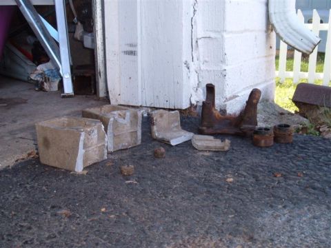 2000 Chevrolet Tahoe - Several concrete blocks and rusty metal automotive parts are laid out on the ground.