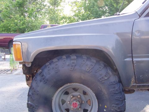 1989 Ford F-250 - A close-up view of a truck's fender and tire, with another vehicle partially visible behind it the background.