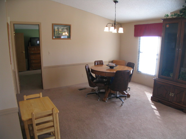 Room interior with dining table and chairs, a china cabinet, and a doorway to another room