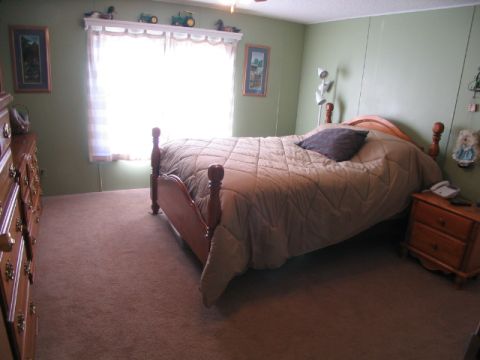1995 Ford Bronco - A bedroom scene a bed with a quilted comforter, a wooden dresser, and a nightstand with a phone.