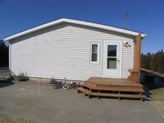 Side of a house with a wooden deck and two bicycles on the concrete
