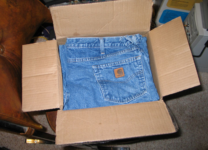 Box with blue jeans inside. Carhartt logo on back pocket