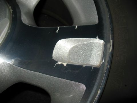 1997 Ford Crown Victoria - A close-up view of a damaged alloy wheel, showing chipped paint and a portion of the tire.