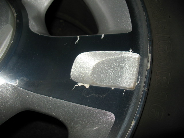 Close-up of a silver alloy wheel with chipped paint and visible tire sidewall