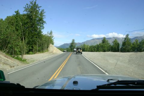 2003 Jeep TJ - Two Jeep Wranglers driving on a highway through a scenic mountain landscape.