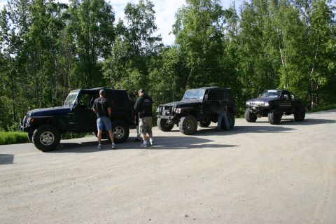 2003 Jeep TJ - A group of Jeep Wranglers, including a 2003 model, are parked together on a dirt road during an outdoor gathering.