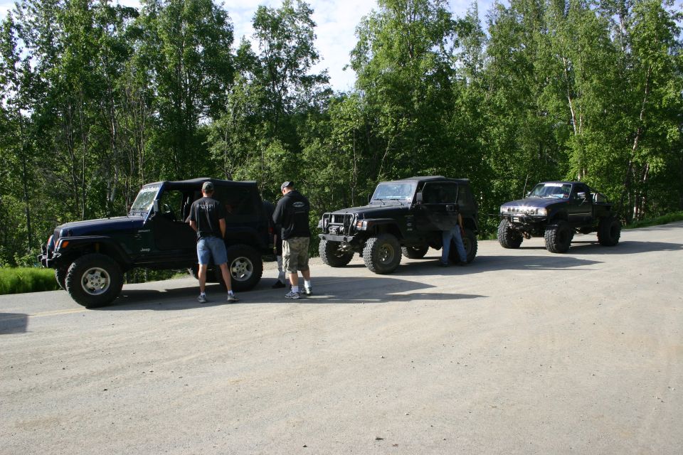 Three black Jeep Wranglers parked side-by-side, two with people standing nearby