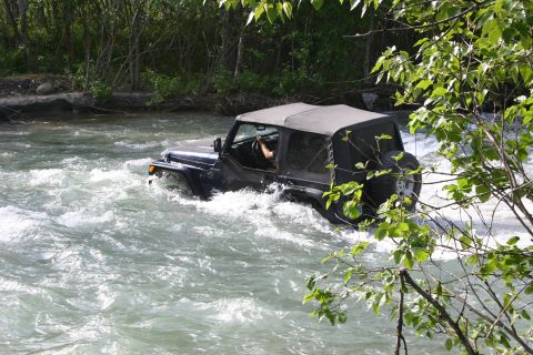 2003 Jeep TJ - A black Jeep Wrangler TJ navigates a rocky river with its soft top deployed.