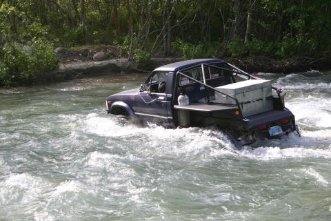 2003 Jeep TJ - This modified pickup truck navigates a fast-moving river, its off-road capabilities.