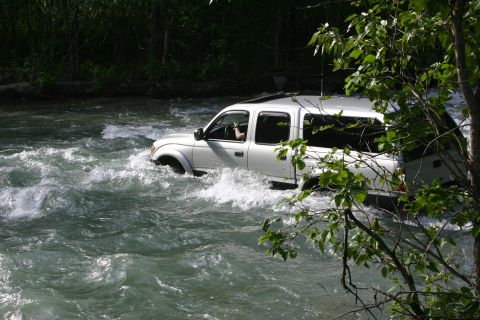 2003 Jeep TJ - A white pickup truck navigates through a fast-flowing river.