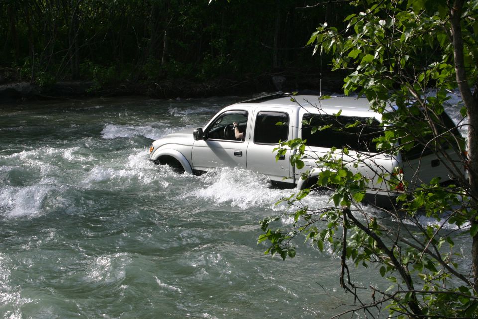 White pickup truck driving through a river, partially submerged