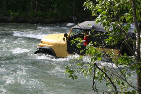 2003 Jeep TJ - A yellow Jeep Wrangler navigates a fast-moving river, its body style indicative of the 1997-2006 model years.