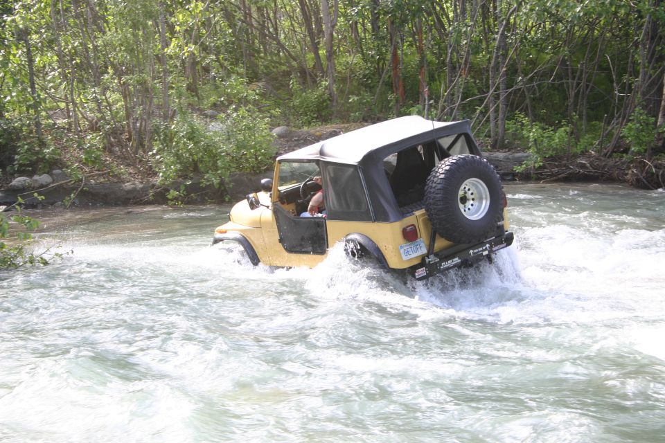 Yellow Jeep TJ driving through a river, rear view