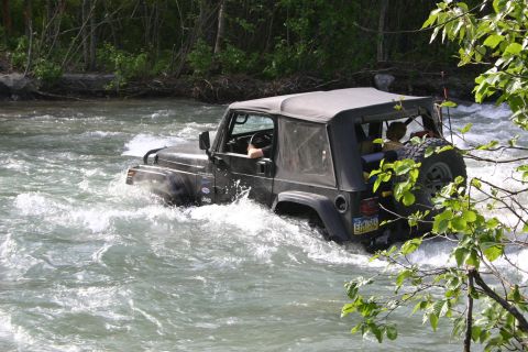 2003 Jeep TJ - A black Jeep Wrangler navigates through a fast-flowing river.