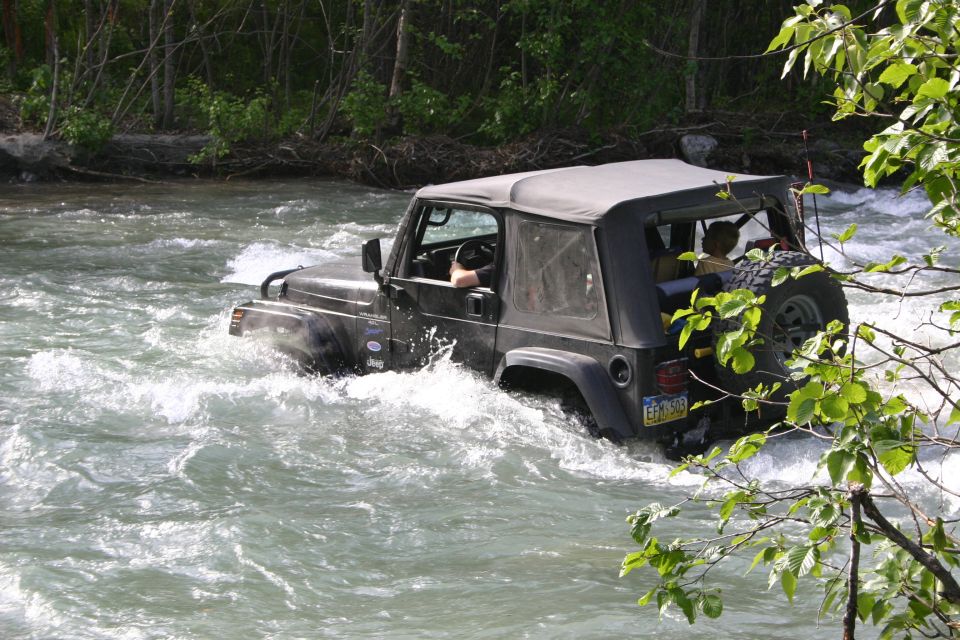 Black Jeep Wrangler driving through a river, water splashing