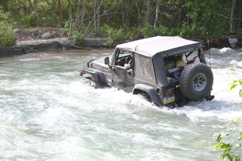 2003 Jeep TJ - A black 2003 Jeep TJ navigates through a fast-moving river, demonstrating its off-road capabilities.