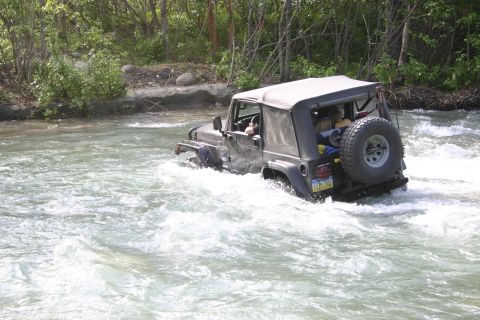 2003 Jeep TJ - Jeep TJ navigates a rocky riverbed, water splashing around its tires.