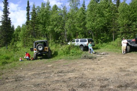 2003 Jeep TJ - A yellow Jeep Wrangler is parked on a dirt road with a wooded area in the background.