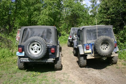 2003 Jeep TJ - Two Jeep Wranglers are parked on a dirt path, with a third vehicle visible behind them.