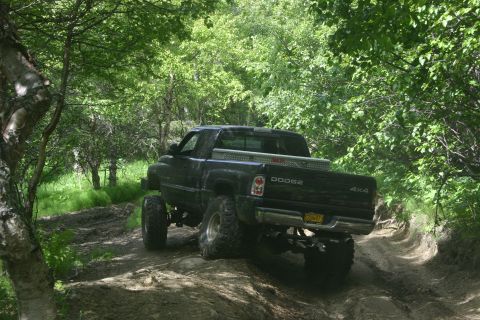 2003 Jeep TJ - Dodge Ram pickup truck navigates a muddy, wooded trail.