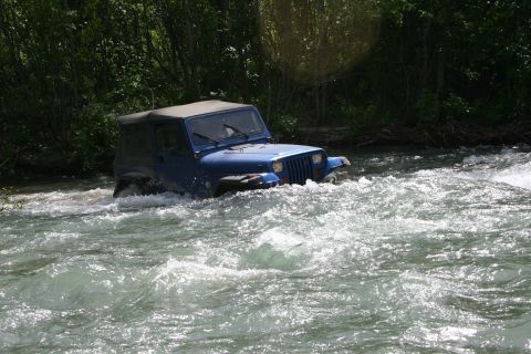2003 Jeep TJ - Blue 2003 Jeep TJ navigates a river, demonstrating off-road capability.