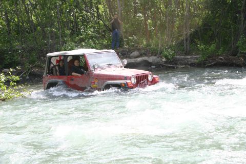 2003 Jeep TJ - A red 2003 Jeep TJ navigates a rocky river during an off-road event.