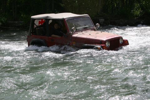 2003 Jeep TJ - Red 2003 Jeep TJ navigates a fast-flowing river with its soft top up.