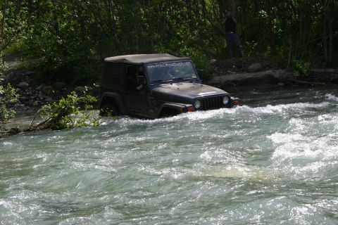 2003 Jeep TJ - A dark blue Jeep Wrangler navigates a river, with a website visible on its windshield.