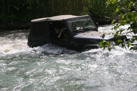 2003 Jeep TJ - A dark blue Jeep Wrangler navigates through river rapids, with a website visible on its windshield.