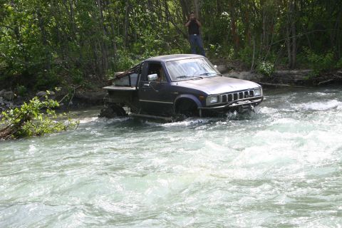 2003 Jeep TJ - Pickup truck navigates a river crossing with significant water flow.