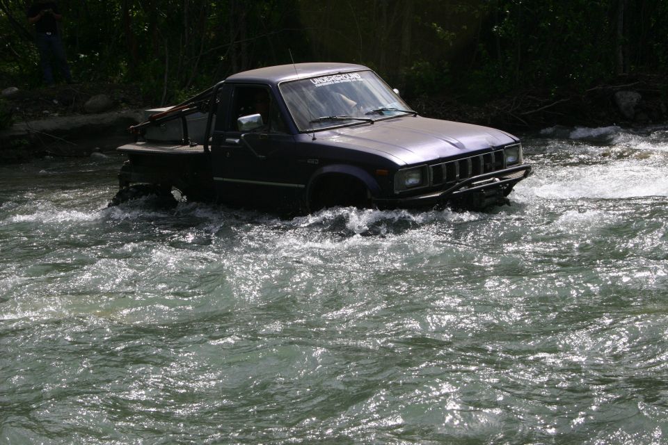 Dark purple pickup truck driving through a river