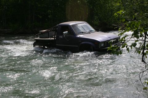 2003 Jeep TJ - Pickup truck navigates a river, showing off its off-road capabilities.