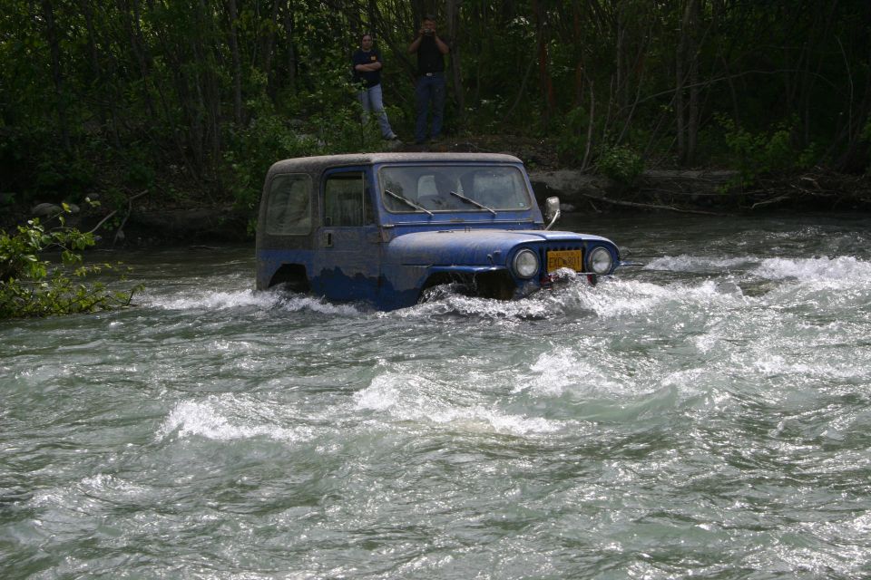 Blue Jeep Wrangler crossing a river, front view
