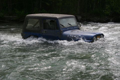 2003 Jeep TJ - A blue Jeep Wrangler navigates through a fast-flowing river.