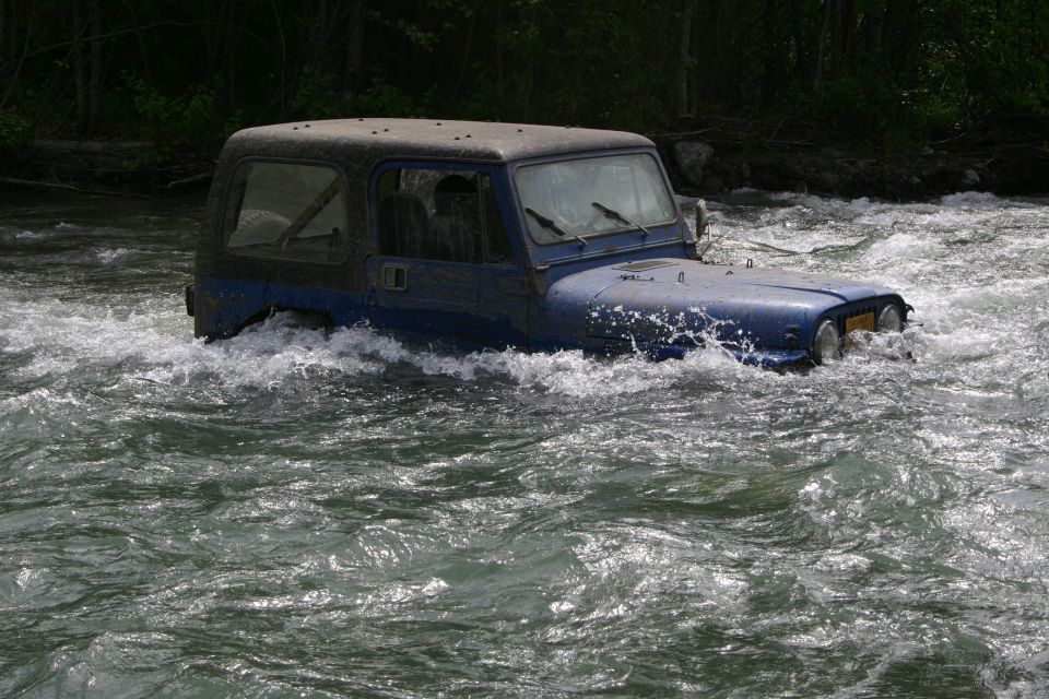 Blue Jeep Wrangler driving through rapids, front view