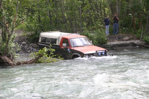 2003 Jeep TJ - Pickup truck navigates a river crossing with two onlookers observing from the shore.