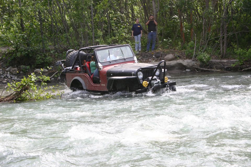Red Jeep Wrangler driving through river, 1997 model year