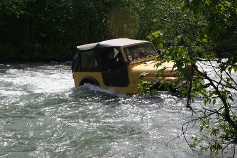 2003 Jeep TJ - A yellow Jeep Wrangler navigates a fast-flowing river, its off-road capabilities.