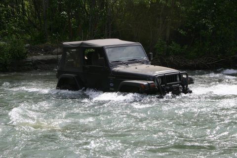 2003 Jeep TJ - A 2003 Jeep TJ navigates a rocky riverbed, kicking up water.